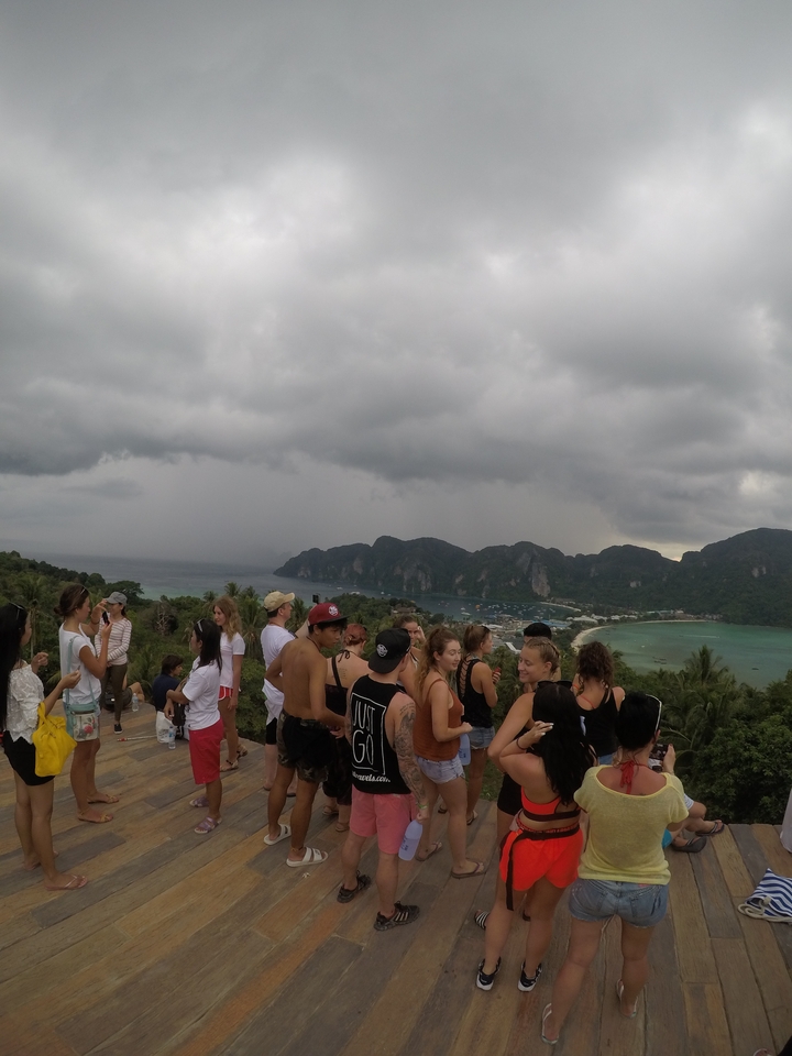 Group of people gathered at a viewpoint with cloudy skies.