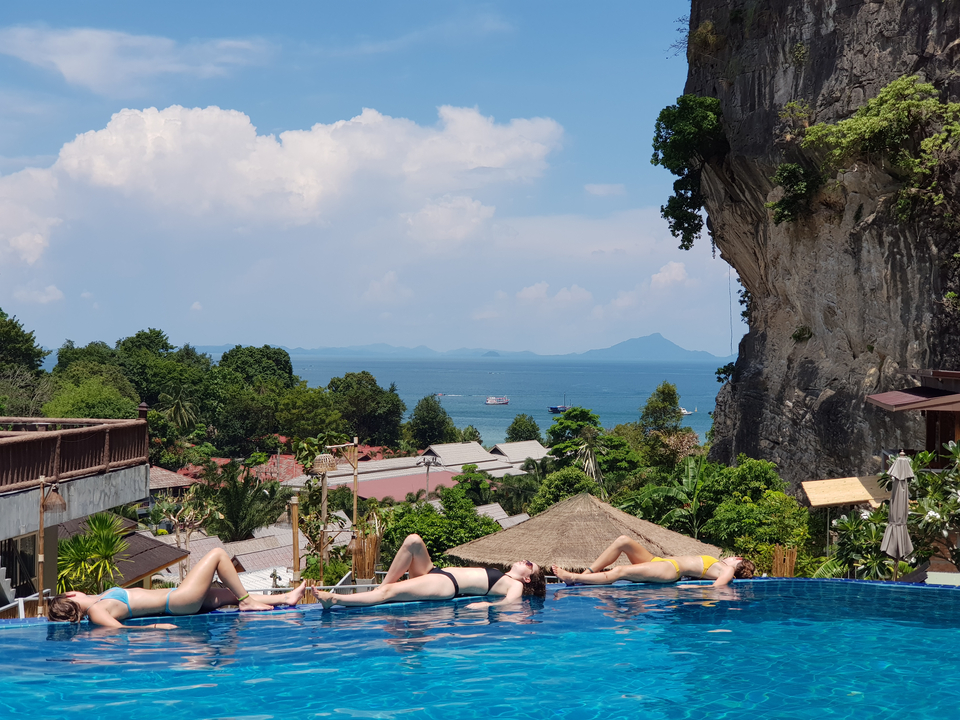 People sunbathing by an infinity pool with ocean view.