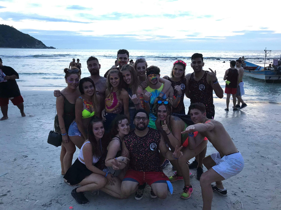 Group of people on a beach at sunset.