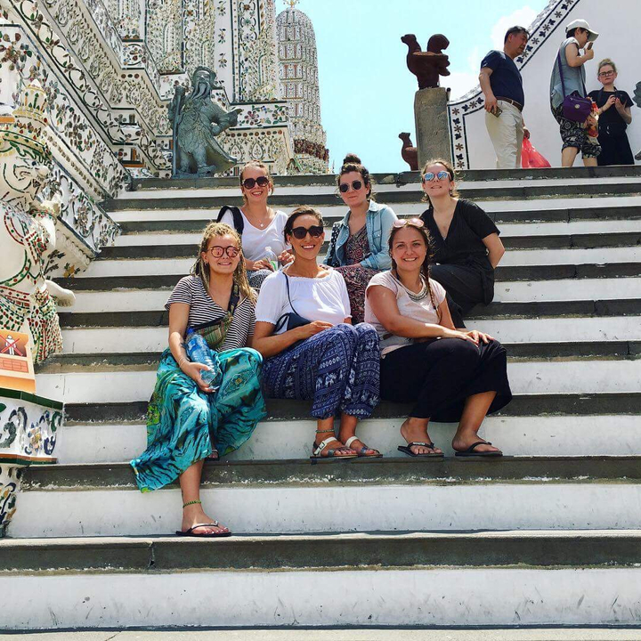 Group of women sitting on stairs, smiling at camera.