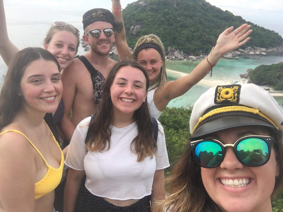 Group selfie with a view of the sea and beach.