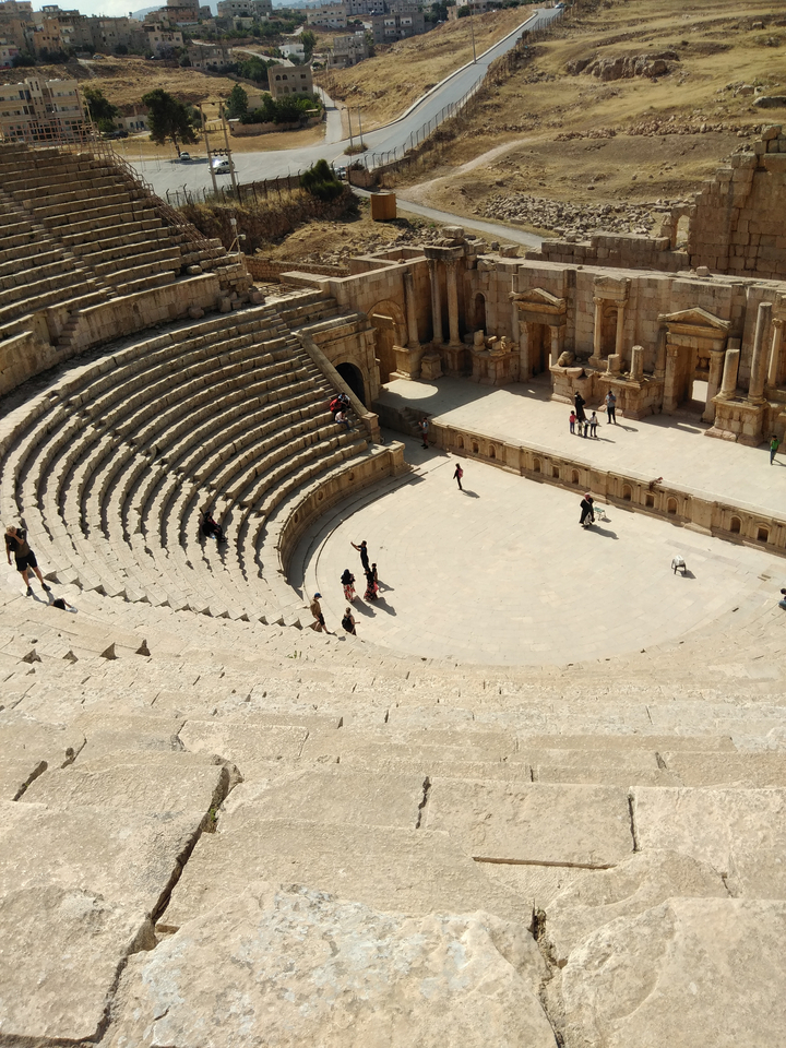 Ancient Roman amphitheater with scattered visitors.
