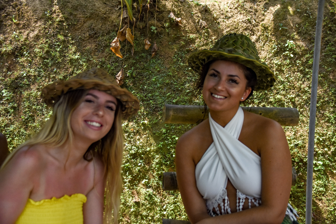 Two women with bamboo hats posing playfully.