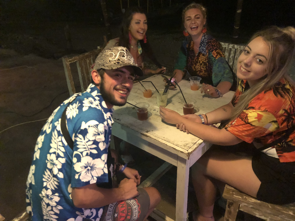 Group of people sitting around a table with drinks at night.
