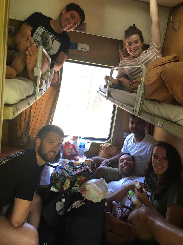 Personnes à l'intérieur d'une cabine de train avec couchettes et casse-croûte.