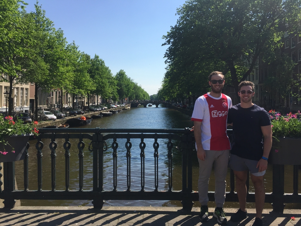 Deux amis posant sur un pont au-dessus d'un canal à Amsterdam pendant la journée.