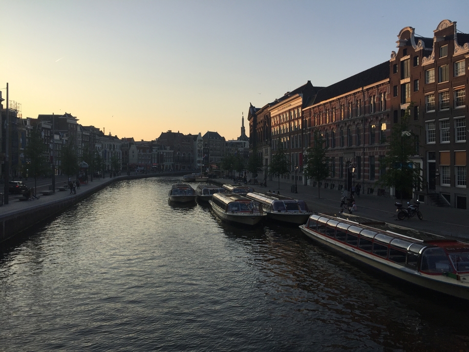 Canal avec des bateaux alignés pendant le coucher du soleil à Amsterdam.