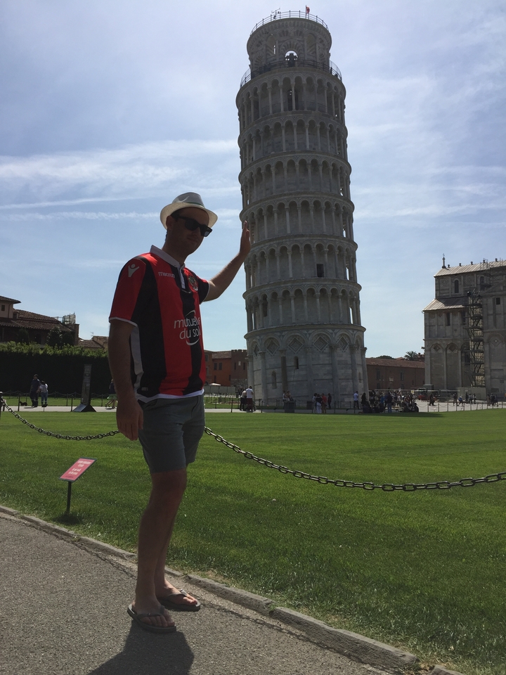 Homme posant avec la tour penchée de Pise.