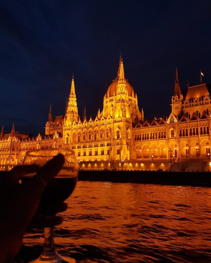 Vue éclairée, le soir, d'un grand bâtiment au bord d'une rivière.