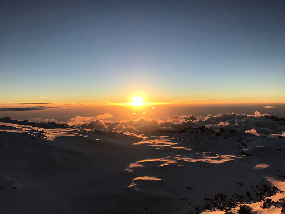 Lever de soleil sur des montagnes enneigées créant une lueur chaleureuse.