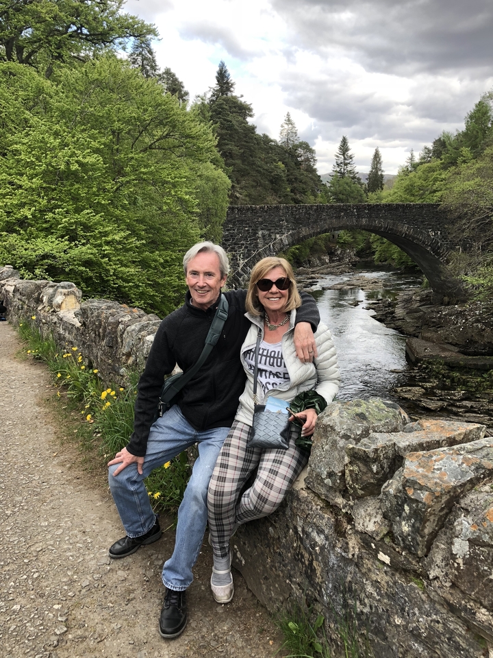 Couple assis sur un pont de pierre au-dessus d'un ruisseau.
