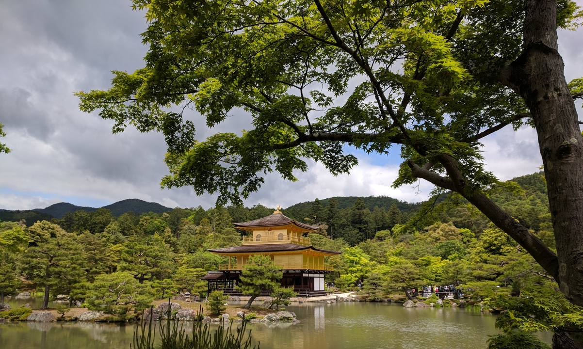 Vue du Kinkaku-ji, le pavillon d'or, entouré d'une végétation luxuriante et d'un étang tranquille.