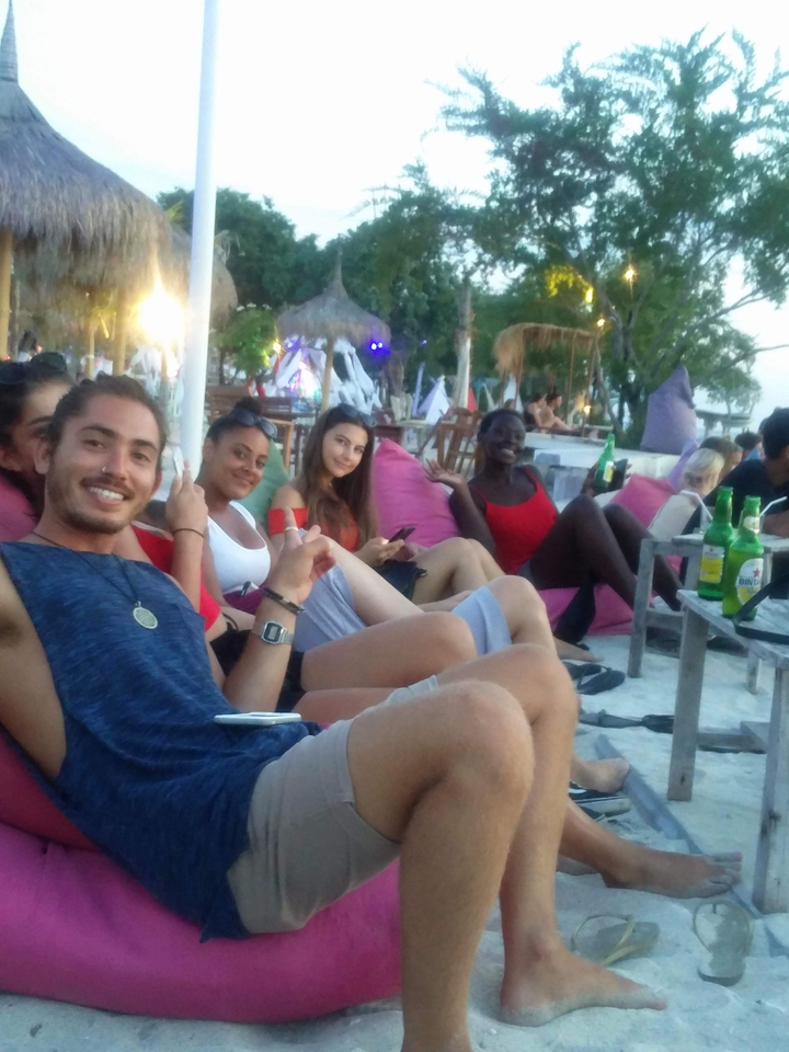 Group of friends enjoying drinks and relaxing on a beach.