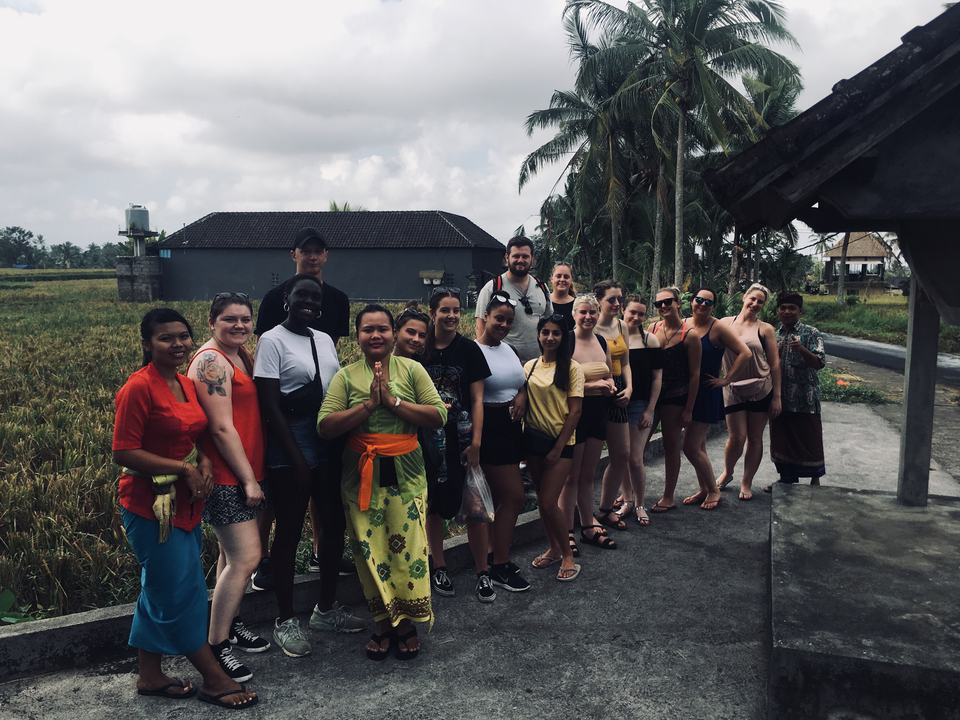 A group of tourists in traditional clothing posing outside.