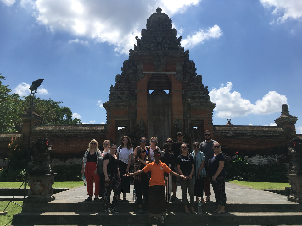 A group of tourists in front of a traditional Balinese gate.