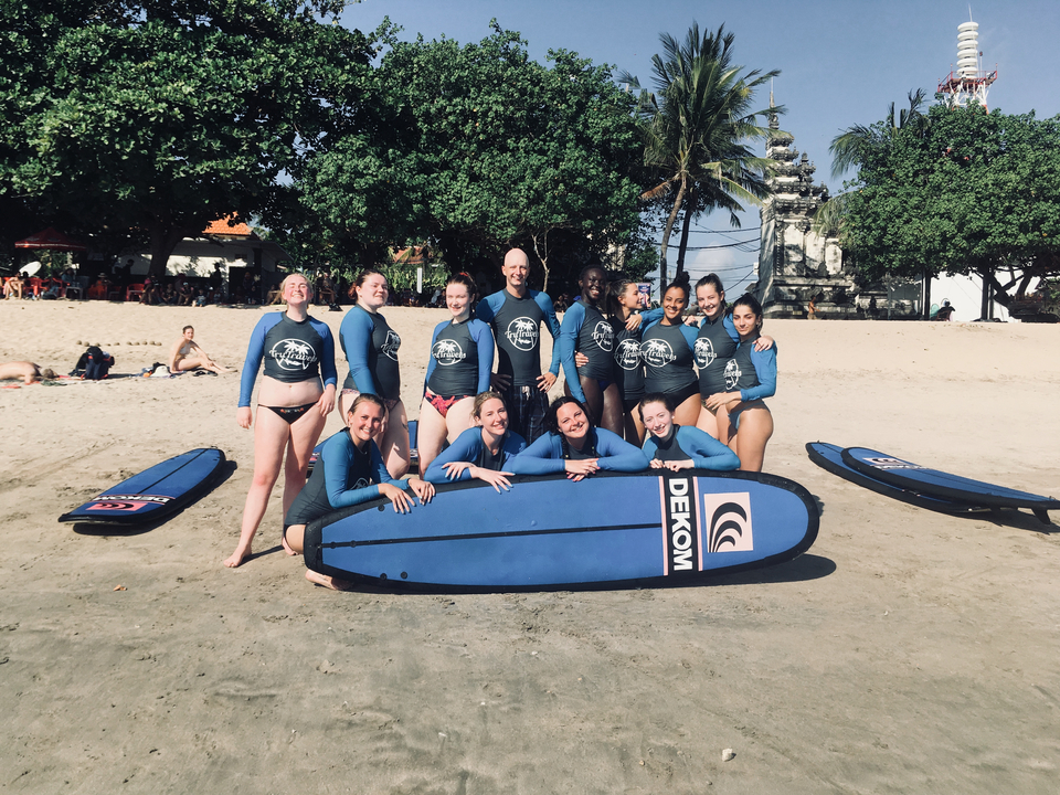 Group of people on a beach with surfboards and wetsuits.
