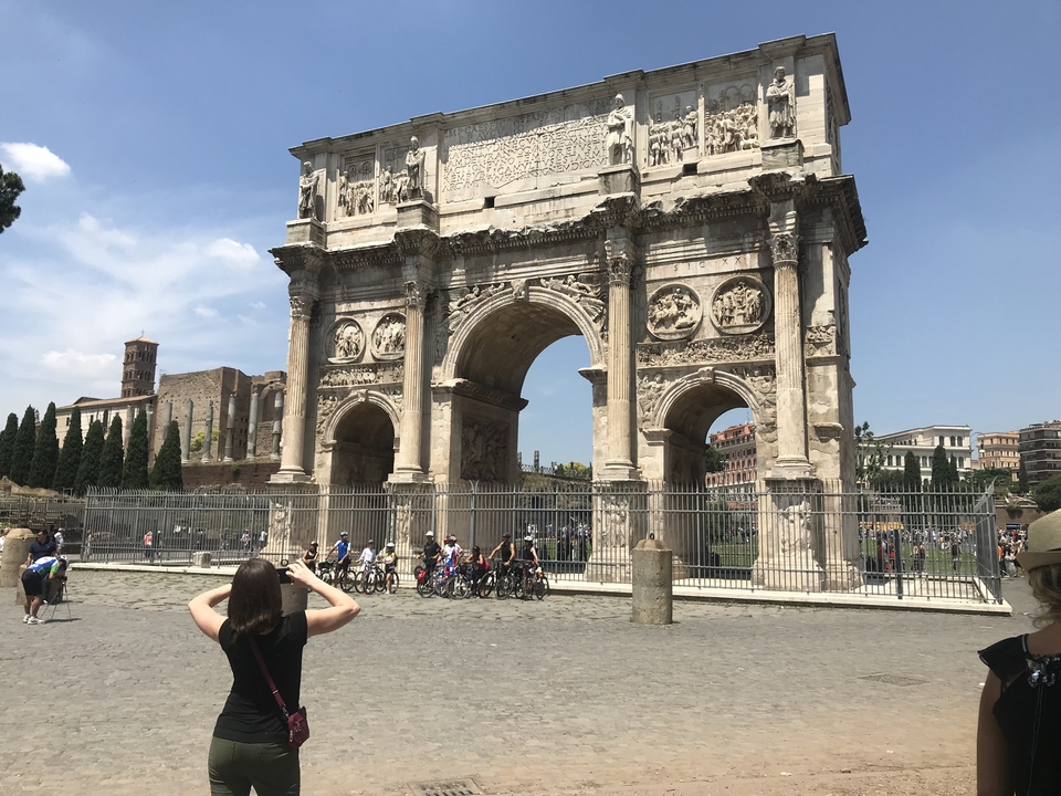 Arc de triomphe historique avec des touristes debout et prenant des photos.