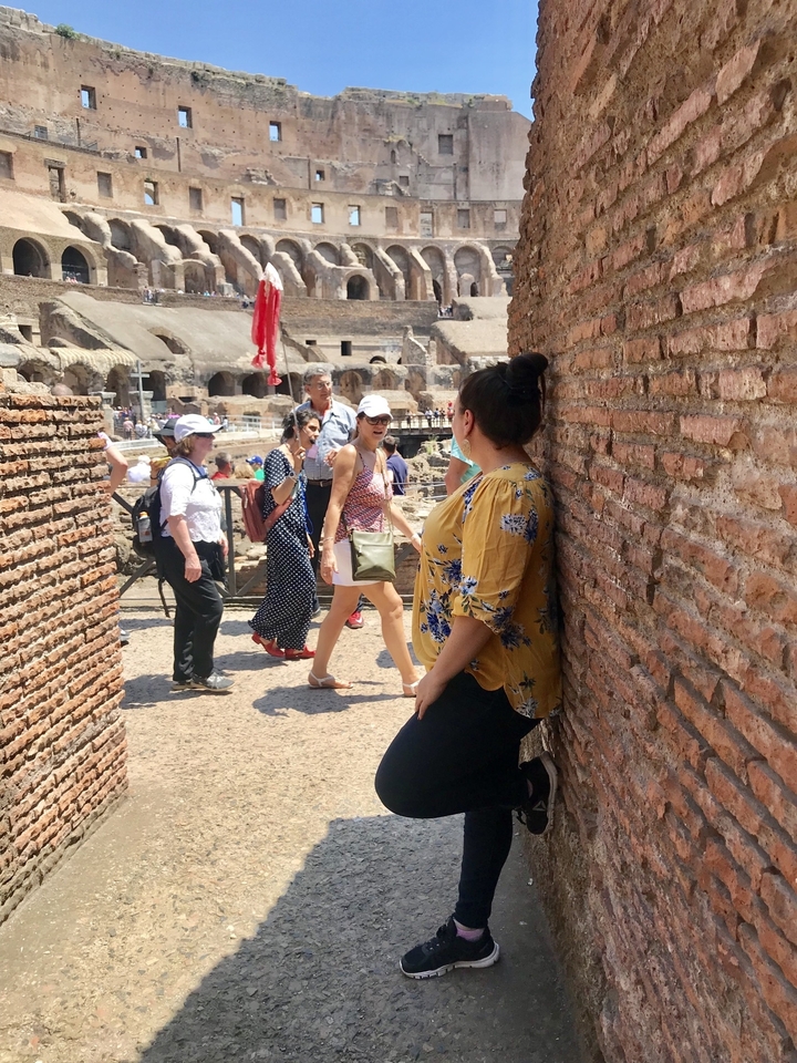 Intérieur d'un site historique avec plusieurs personnes, avec en point de mire une femme adossée à un mur de briques.
