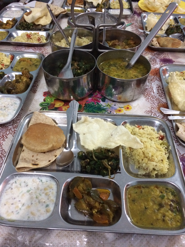 Repas traditionnel indien présenté sur un plateau d'argent avec divers plats et ustensiles.