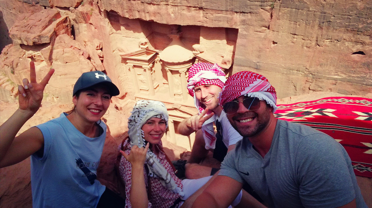 Group sitting on rocks with Petra Treasury in the background.