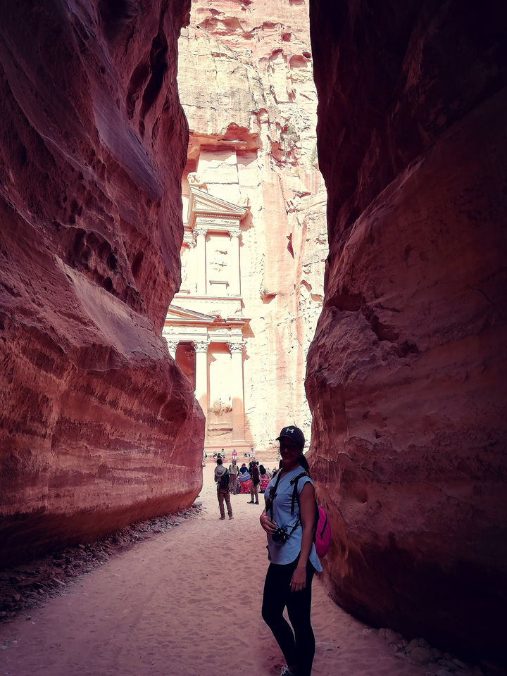Personne debout dans un canyon étroit avec vue sur le Trésor de Petra.
