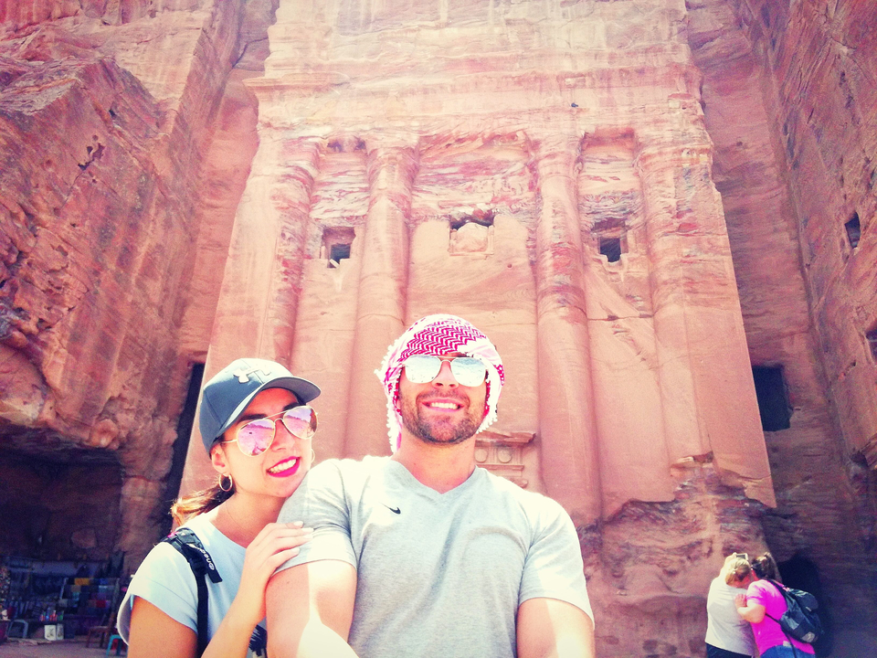 Couple with arm around each other in front of an ancient stone building.