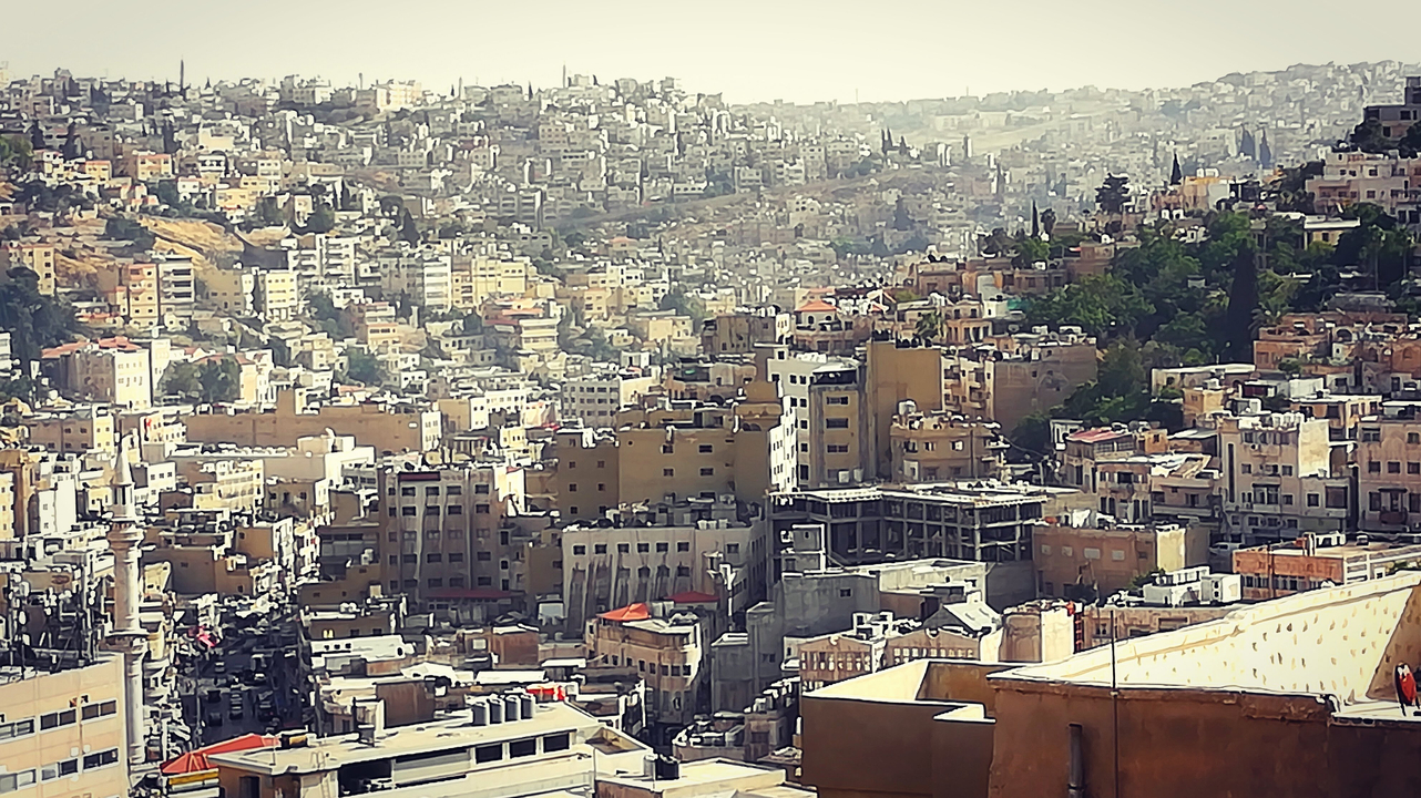 Panoramic view of a densely built city with hills in the background.