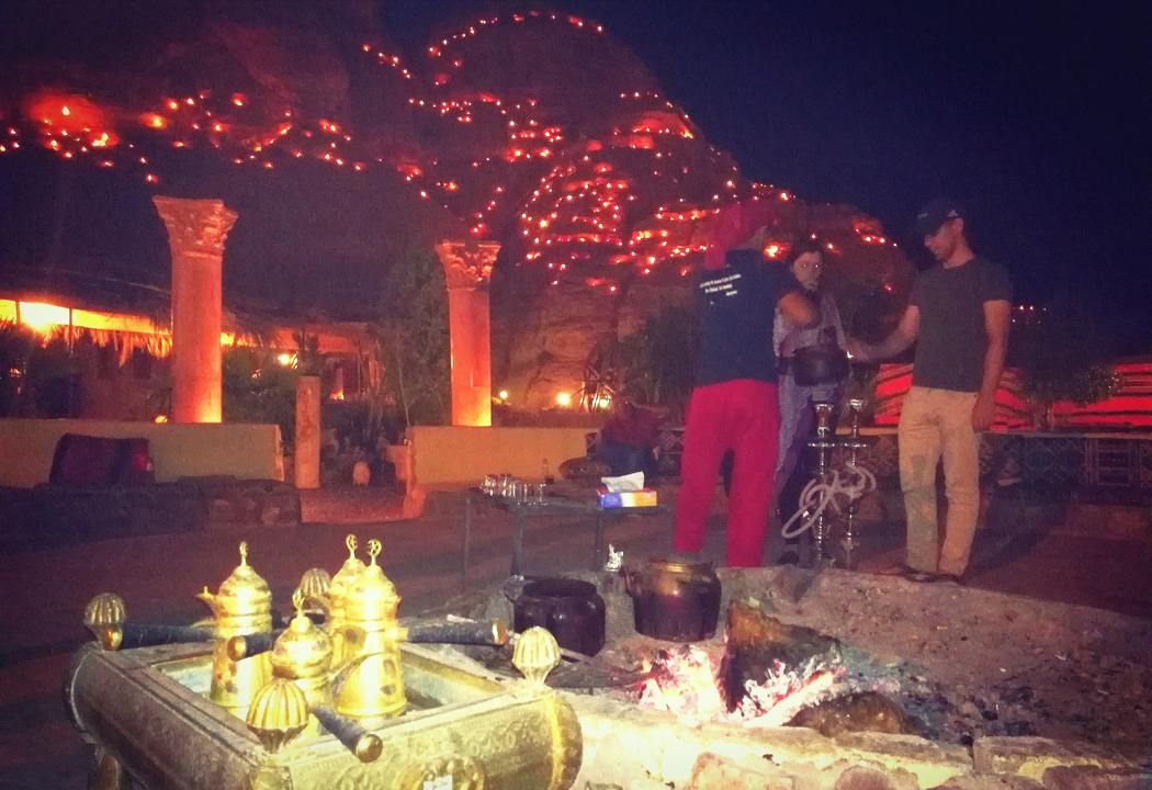 Personnes préparant du thé ou du café dans un décor désertique nocturne.