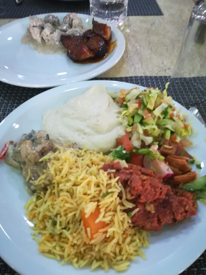 Plat composé de riz, de légumes et de sauce sur une natte tissée.