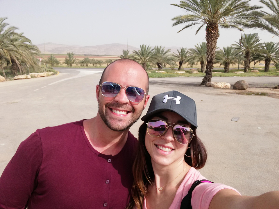 Couple prenant un selfie dans une zone désertique avec des palmiers.