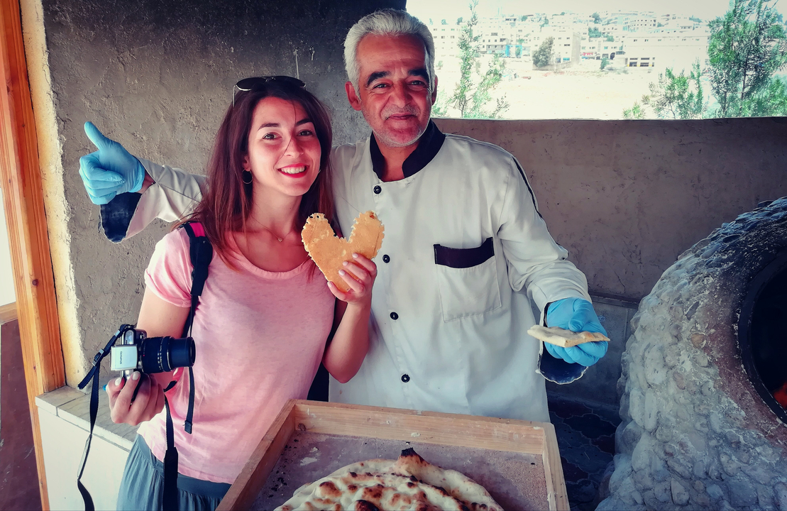 Deux personnes posant avec un pain en forme de cœur dans un cadre rustique.