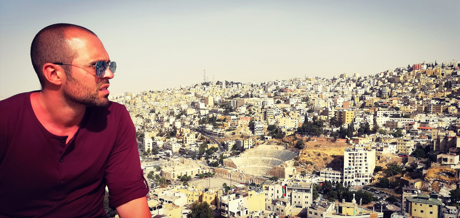 Man overlooking a cityscape with hills in the background.