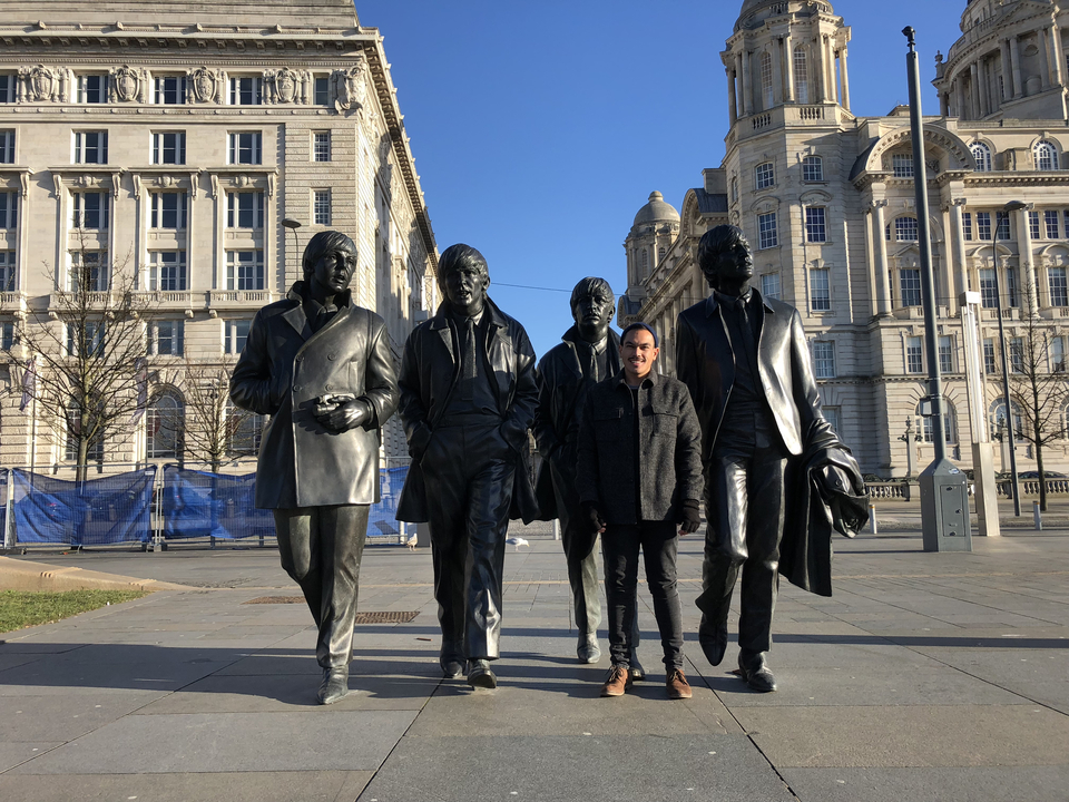 Personne posant avec des statues célèbres dans un environnement urbain.