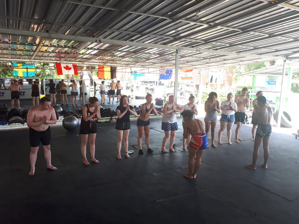 Group of people practicing Muay Thai under a shelter.