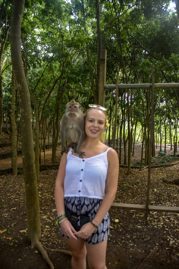 Person with a monkey on shoulder in a forest.