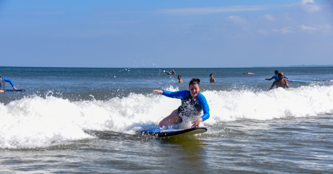 Person surfing on a wave with several people in the background.