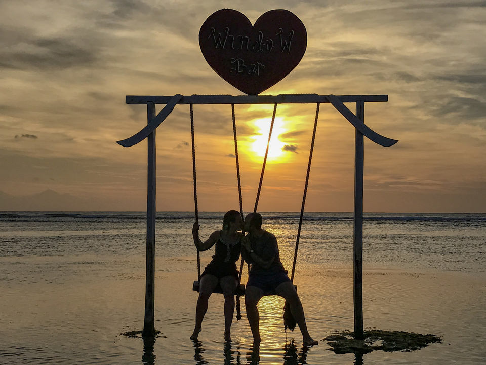 Couple on a swing during sunset at the beach.