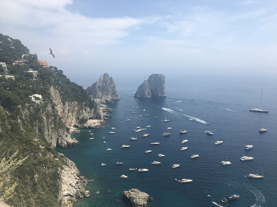 Les formations rocheuses Faraglioni dans la mer bleue avec des bateaux.