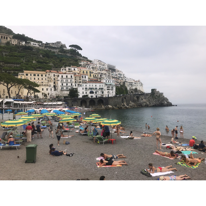 Une plage avec des parasols colorés et des gens qui se détendent sur le sable.