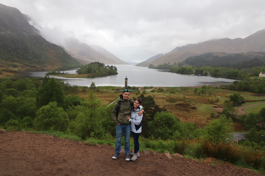 Couple posant devant un lac et des montagnes.