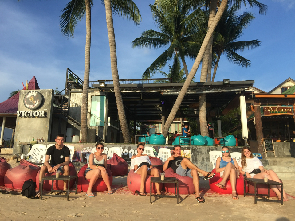 Group sitting on colorful bean bags at a beach bar.