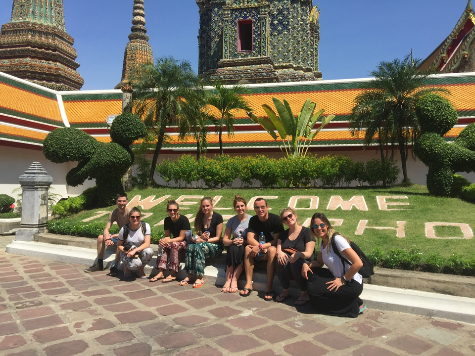 Group sitting in front of a temple with welcome hedge.