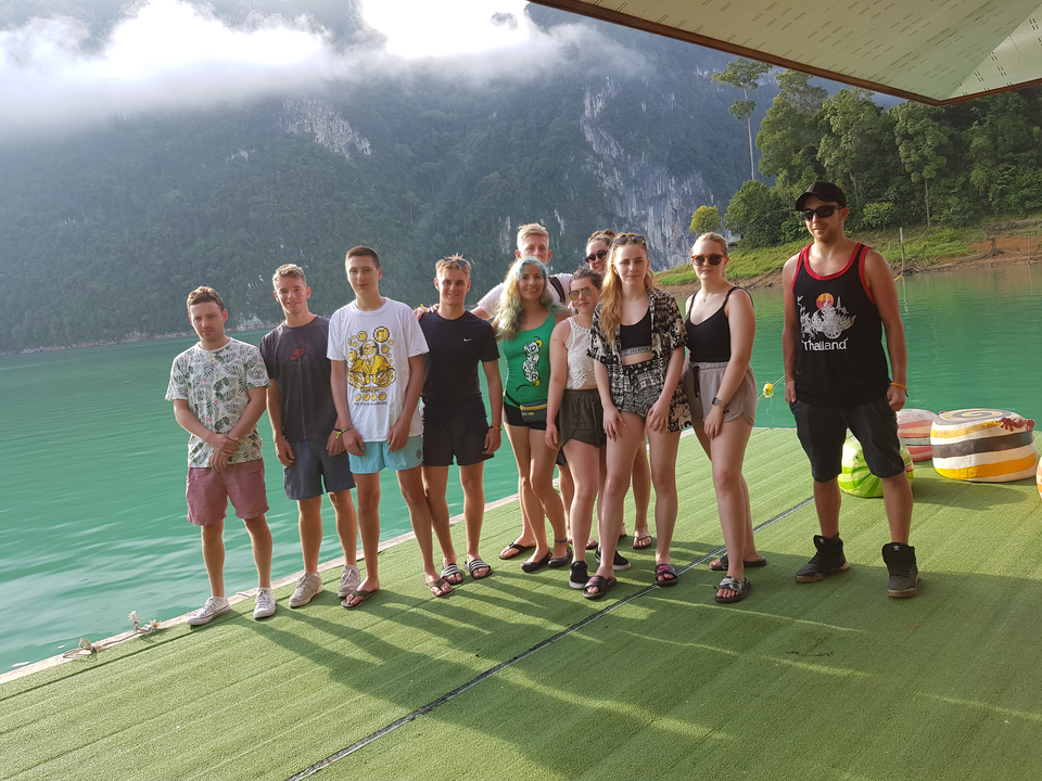 Groupe de jeunes gens posant sur un quai flottant sur un lac.