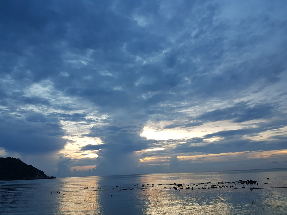 Coucher de soleil sur un océan calme avec des nuages spectaculaires dans le ciel.