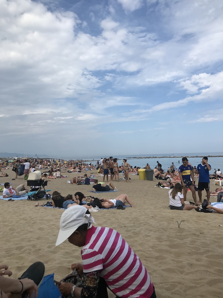 Crowded sandy beach with people relaxing and enjoying the sun.