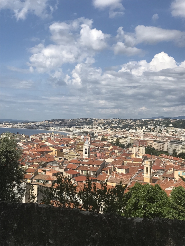 Scenic view overlooking coastal city with red rooftops and a distant beach.