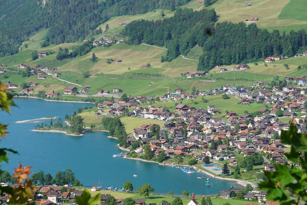 Overlooking view of a lake surrounded by green hills and villages.
