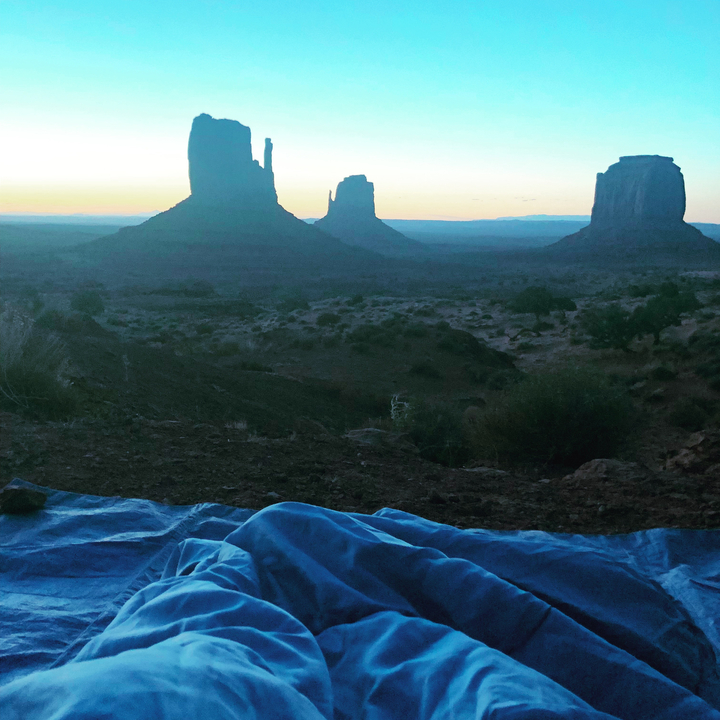 Un sac de couchage installé parmi des formations rocheuses au lever du soleil.