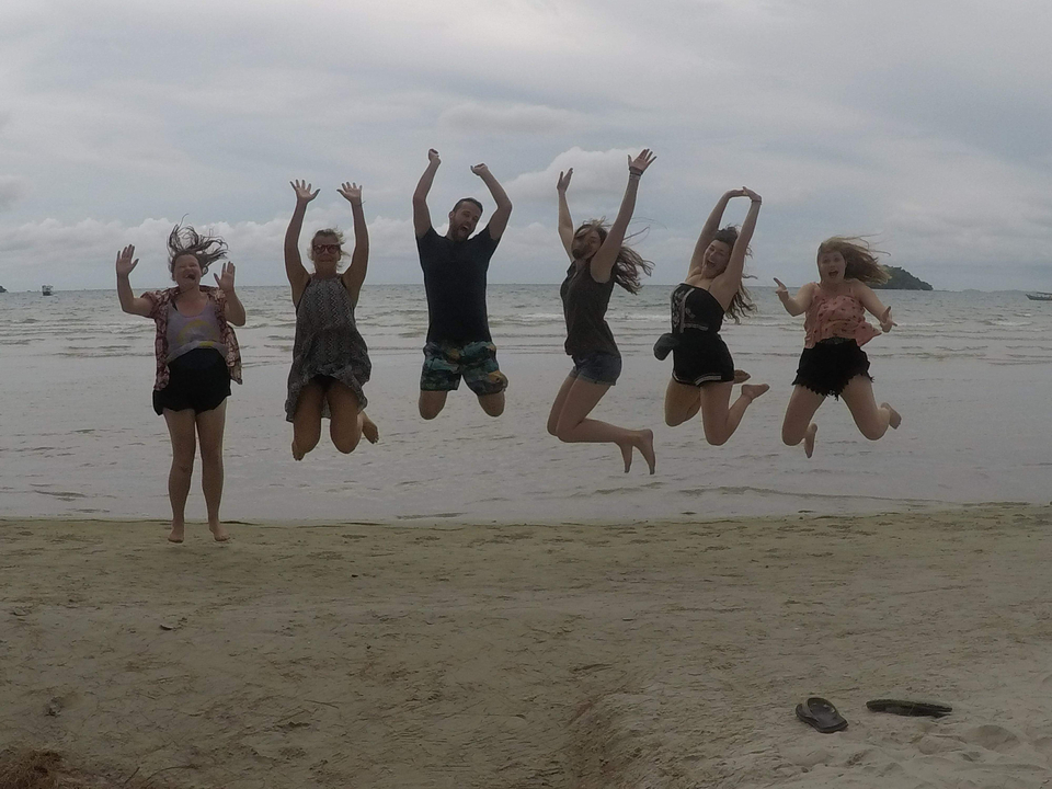 Group of people jumping on a beach.