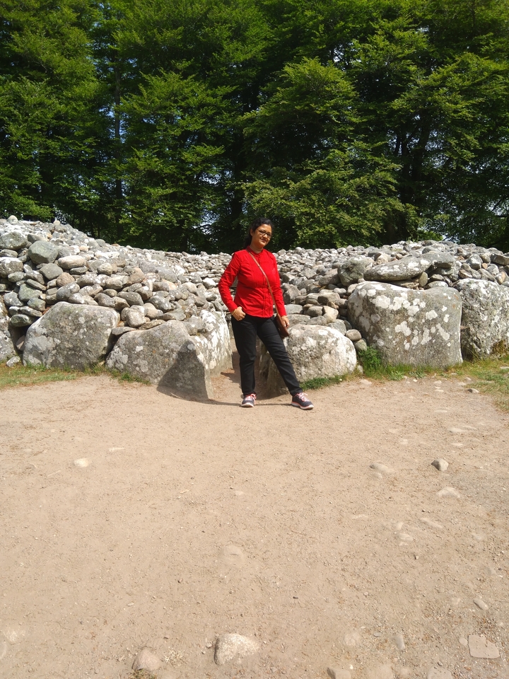 Femme debout devant un cairn de pierre.